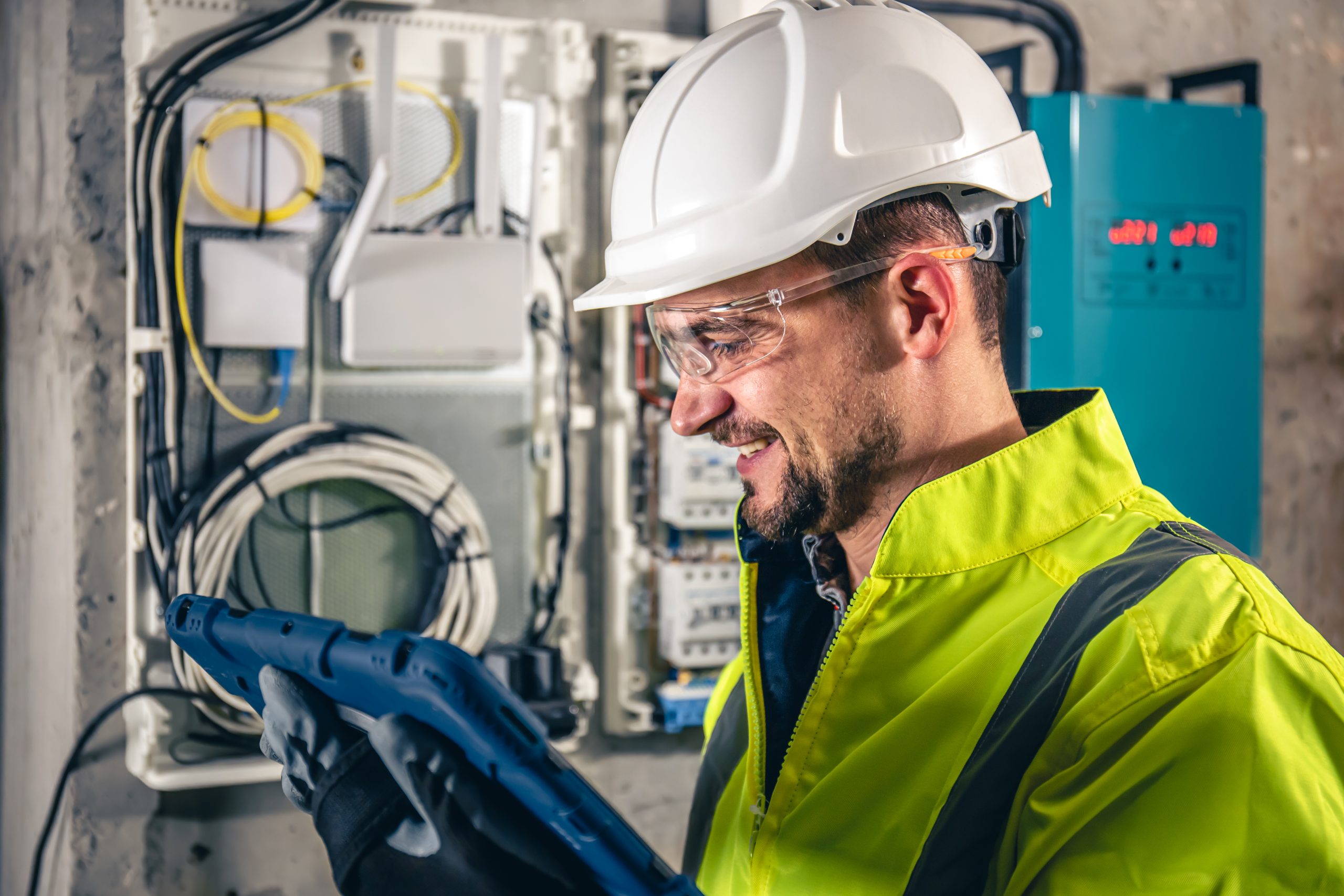 Home man, an electrical technician working in a switchboard with fuses, uses a tablet.